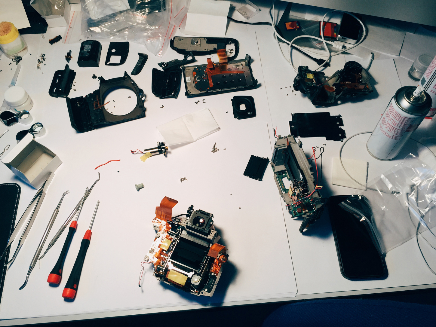 Top view of desk with demage devices needed repairing. Someone uses tools for fixing camera and other electronic gadgets. Maintenance concept